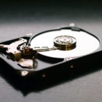 An illustration comparing a fragmented hard drive to a disorganized library. On the left, books are scattered randomly on a shelf, representing fragmented data. On the right, the books are neatly organized, representing a defragmented computer hard drive