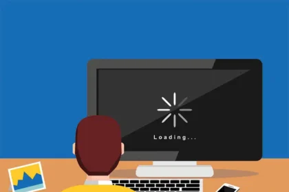 A frustrated person holding their head in their hands while staring at a laptop with a persistent loading symbol on the screen, illustrating the topic of a computer running slowly